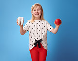 happy modern girl showing tooth and an apple on blue