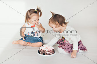 Two little baby girl eating cake isolated white background