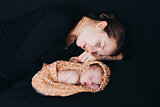 a woman and a newborn baby sleep on a black background. Mother and child