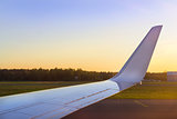 Wing of aircraft over the runway at sunset. Riga