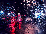 Blurred traffic lights bokeh with rain drops on glass