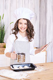 Light wooden background. Cooking buns. Girl with tablet in kitch
