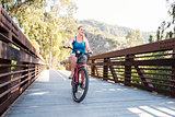Young blond female riding a beach cruiser bike over a bridge