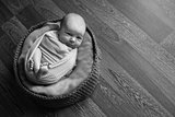 Portrait a little child in a cap lies on a basket. Face of newborn