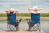 young relaxed couple near a picturesque lake sitting on chairs o