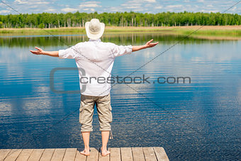 free happy man enjoys the beautiful nature near the lake, view f