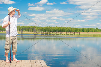 portrait of a fisherman on a pier looking away into the lake