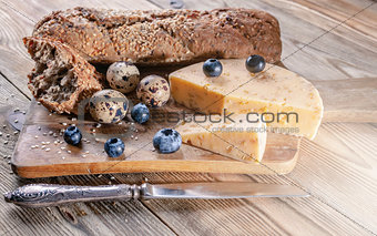 Baguette, cheese with spices and herbs, quail eggs, blueberries. Tasty and healthy bio food concept