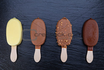 Ice cream on stick covered with chocolate on black slate 