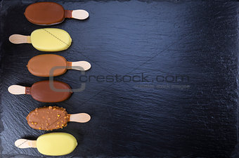 Ice cream on stick covered with chocolate on black