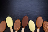 Ice cream on stick covered with chocolate on black