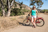 Young blond female looking off with a beach cruiser bike on a ride outdoors