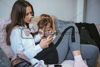 Mom and daughter are looking at the smartphone