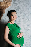 Portrait of pregnant woman in long dress on white background