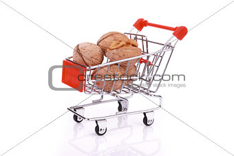 Walnuts in miniature shopping cart isolated on white background
