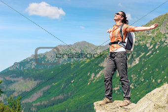 portrait of a happy woman conquering a high mountain with a back