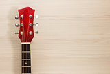 Guitar acoustic red, the neck lies on the wooden wall light background classical Spanish, rectangular format music school game for children and adults close-up of fingerboard and strings, the soundboard of the instrument, the Wallpapers Close-up of guitar