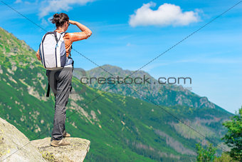 a tourist with a backpack in the mountains on a precipice lookin