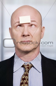 Businessman with a blank note on his forehead