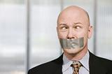 Cross-eyed businessman muzzled with duct tape