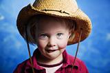Little girl in front of blue wall with a cowboy hat