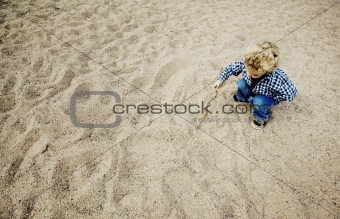 Little Boy Drawing in the Sand