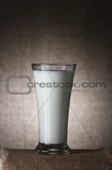 single Glass of Milk on burlap canvas and brown rustic backgroun