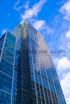Skyscraper reflecting the blue sky with bright clouds