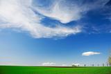 Green field, white clouds, blue skies