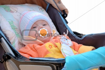Little girl with baby's dummy sit in carriage.