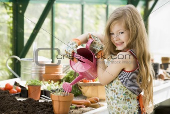 Young girl watering plants in greenhouse