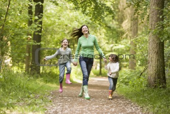 Mother running along woodland path with 2 children
