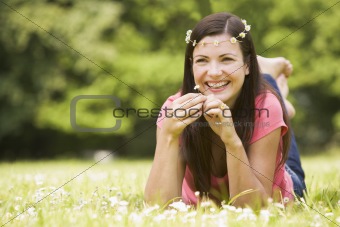 Woman relaxing in field on daisies