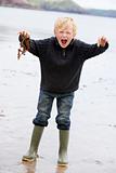 Young boy holding seaweed at beach