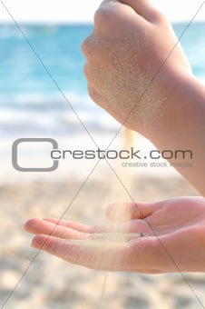 Hands pouring sand on a beach