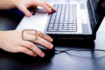 Male hands on notebook keyboard and mouse