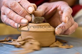 Potter shaping  a cup base on a spinning wheel