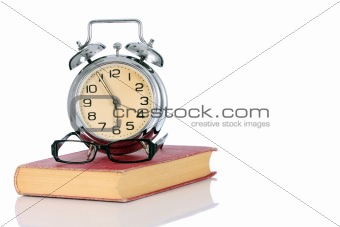 book with alarm clock and eyeglasses 