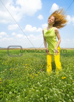 Young woman standing on a green field flipping hair back