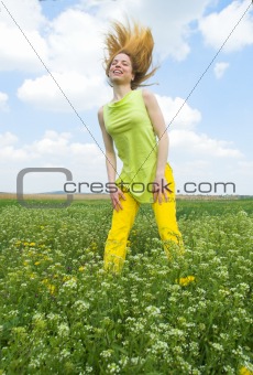 Young woman standing on a spring time field, flipping hair back