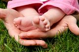 Mother's hands cradling her infant Daughter's feet