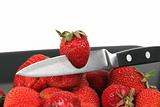 strawberries with knife on Black Plate over White 