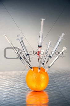 Syringes inserted into an orange