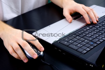 Male hands on a notebook keyboard and mouse
