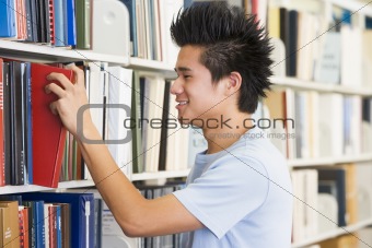 University student selecting book from library shelf