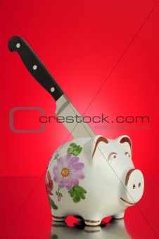 piggy bank with knive in his back on red background