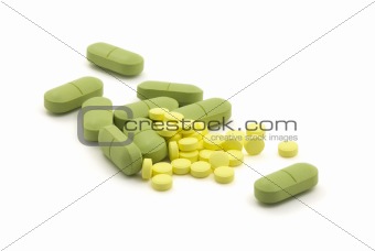 Green and yellow pills with dose on white background
