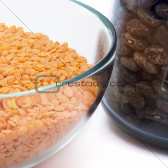 abstract image of glass jars filled with red lentils and haricot against white background
