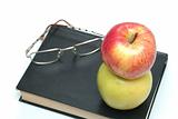 Glasses and apple are on the book