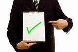 Green tick on clipboard in the hand of a businessman